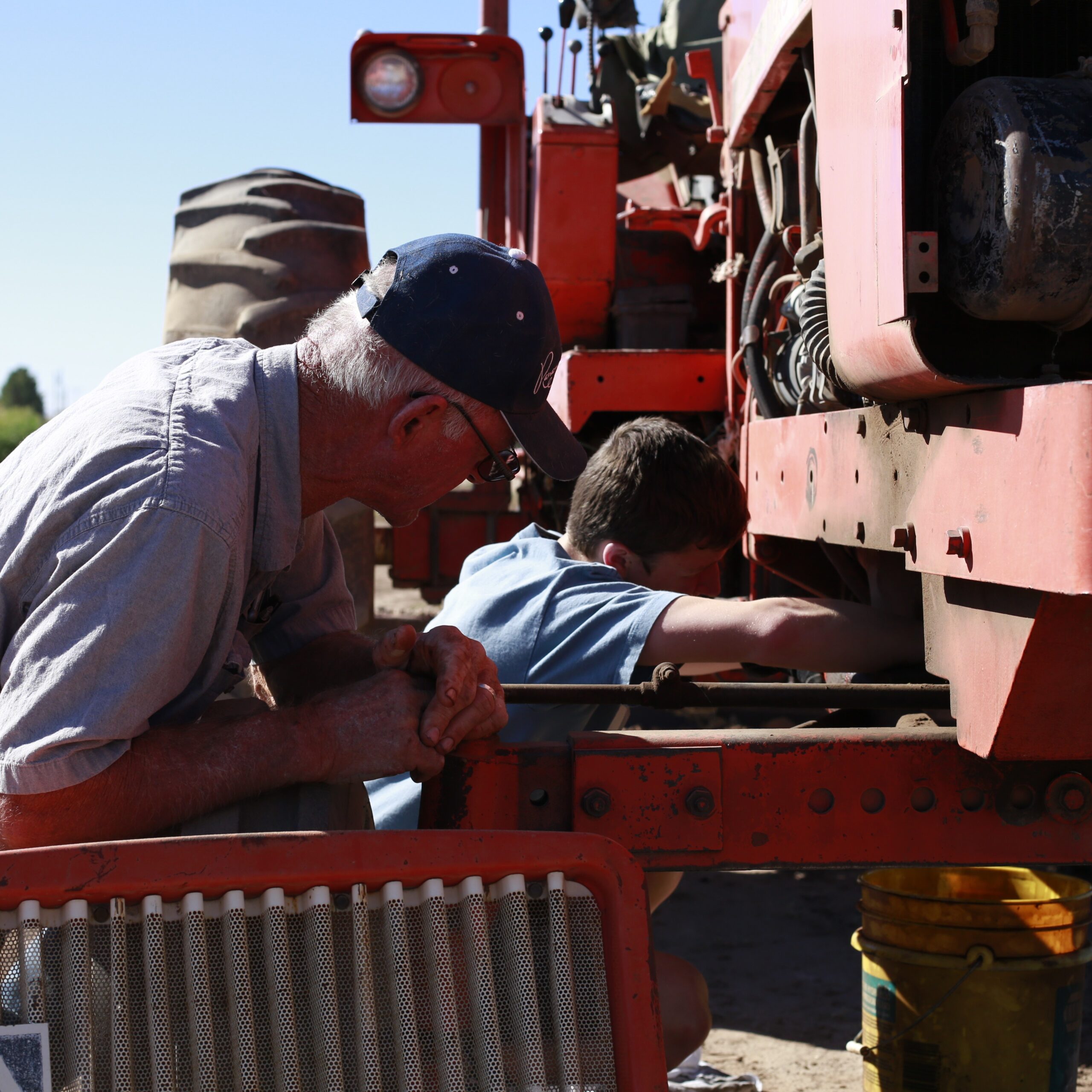 Grandfather and grandson working on ag machinery